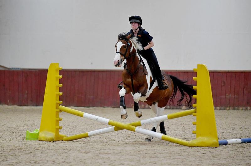 Young rider jumping a cross pole